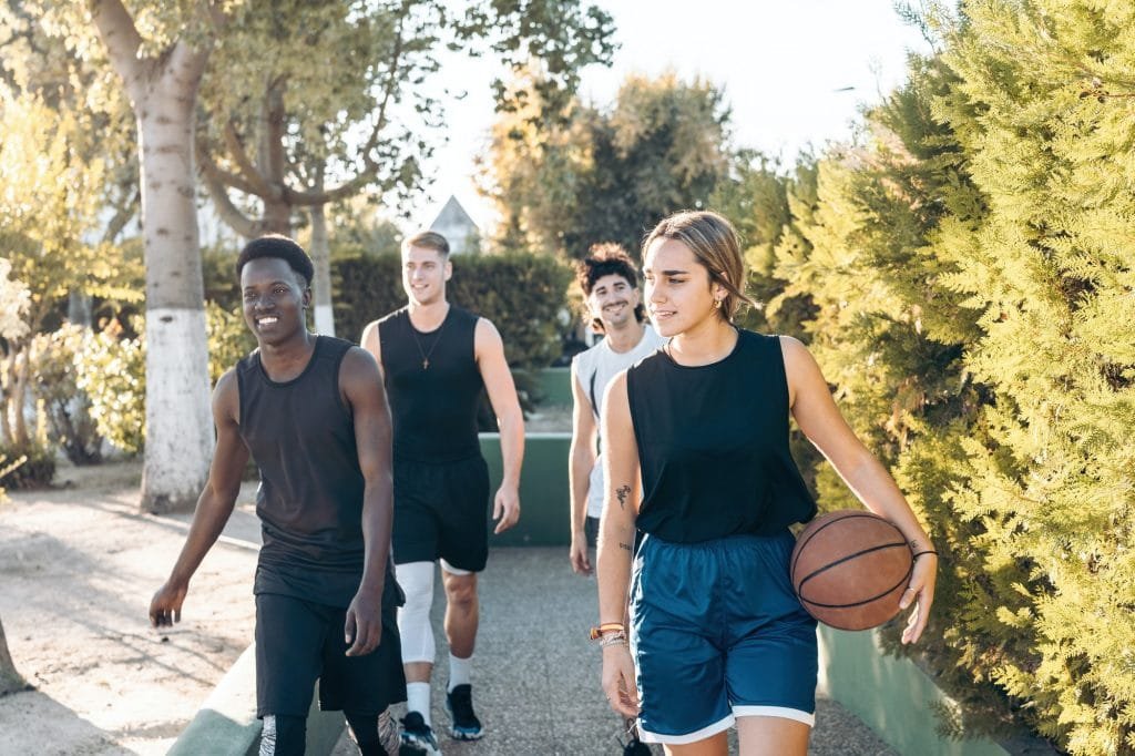 Four friends walking to a path with a basketball ball