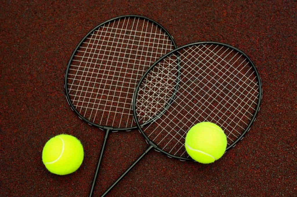 Badminton rackets and tennis balls on playground rubber coating